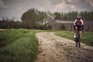 Fahrerin fährt auf steinigen Landweg bei Roubaix