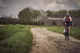 Fahrerin fährt auf steinigen Landweg bei Roubaix
