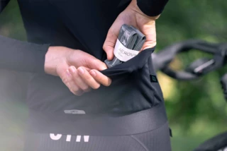 Frau verstaut einen AERON/TPU Gravel-Schlauch in der Rückentasche ihres Fahrradtrikots und zeigt damit das praktische und kompakte Packmaß unserer Fahrradschläuche.