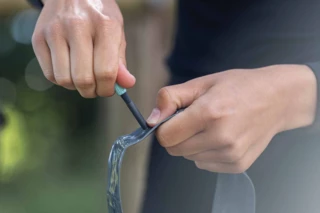 Türkise Ventilkappe eines nicht montierten AERON/TPU Schlauches wird mit der Hand abgeschraubt.