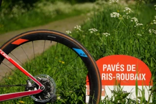 Fahrrad lehnt an Schild mit Aufschrift "Pavés de Paris-Roubaix"